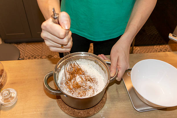 A person whisks the sauce in a pot
