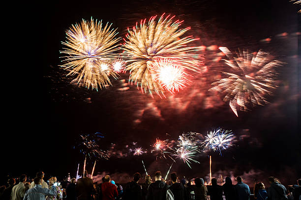 istock Fireworks over waterfront with crowd watching night celebration, long exposure light trails and festive atmosphere. g. 2262285795