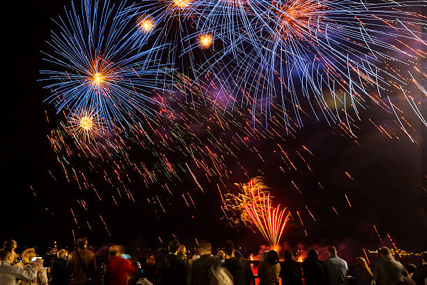 istock Fireworks over waterfront with crowd watching night celebration, long exposure light trails and festive atmosphere. g. 2262286107