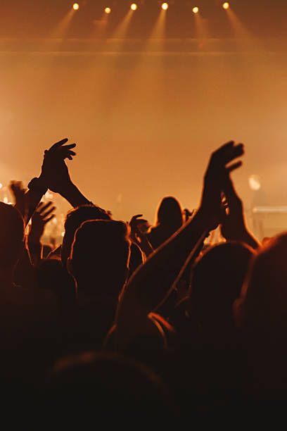 Silhouetted audience clapping hands at live performance