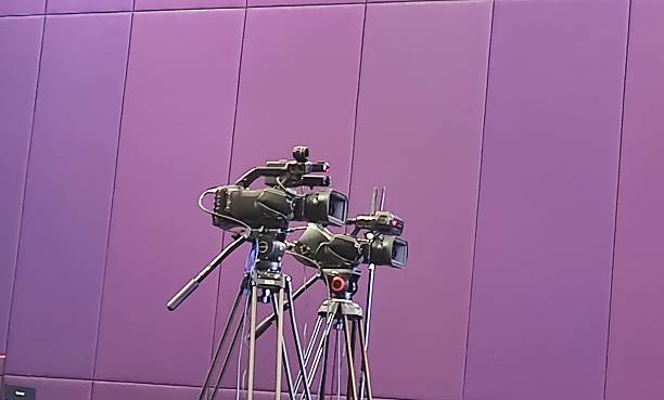 Jakarta, Indonesia - Feb 04, 2026: Two Professional Broadcast Cameras on Tripods in a Modern Studio with Purple padded Walls