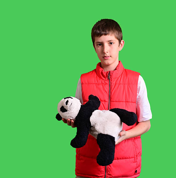 A caucasian kid hugging teddy bear stuffed animal over green background