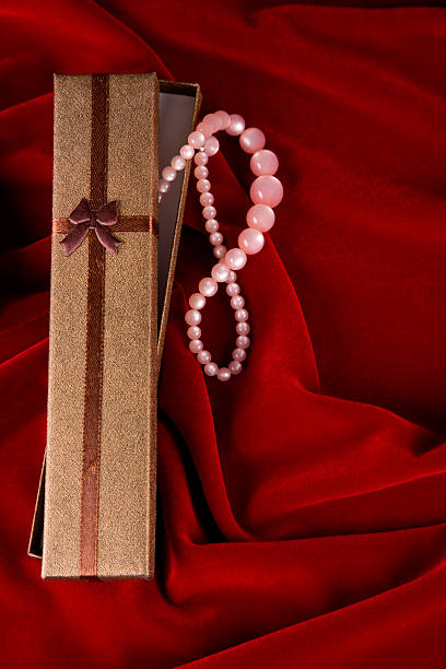 Elegant gift box with pearls and copy space on red velvet background