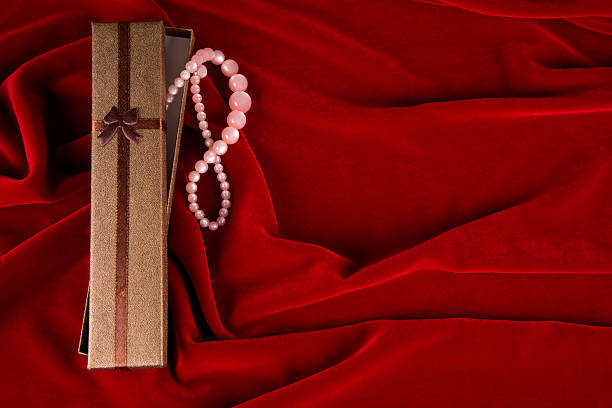 Elegant gift box with pearls and copy space on red velvet background