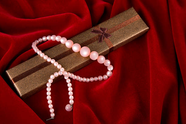 Elegant gift box with pearls and copy space on red velvet background