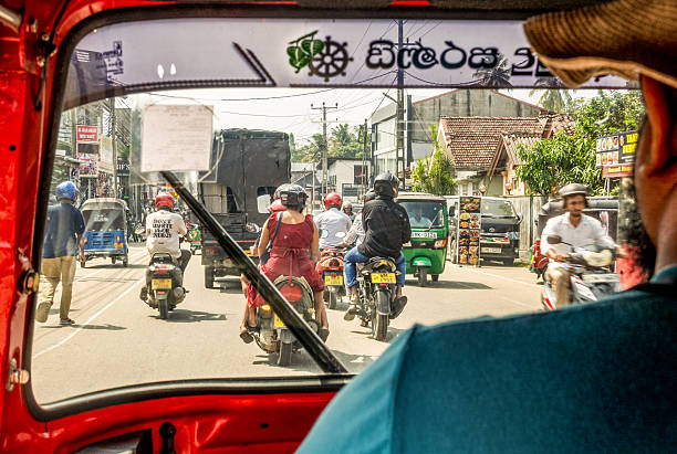 Bentota, Sri Lanka - A view of a busy daytime street, looking over the shoulder of a tuk-tuk driver.