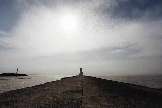 A lighthouse in the fog along the shores of Lake Huron. The sun is trying to break through the fog. Shot with a Canon 5D Mark IV.