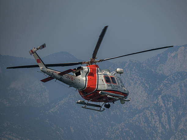 Search and rescue helicopter of Turkish Coast Guard in flight. Rear perspective view shows aircraft equipment and markings against rugged mountain background in Antalya, Turkey.