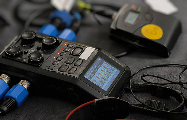 Close-up of a portable digital audio recorder with multiple inputs and a wireless receiver unit, ready for on-location sound capture