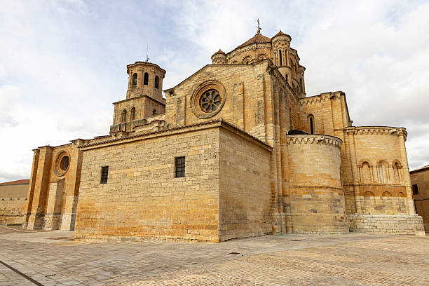 A large building with a clock tower and a cross on top in Toro, Spain. The building is made of stone and has a lot of windows.