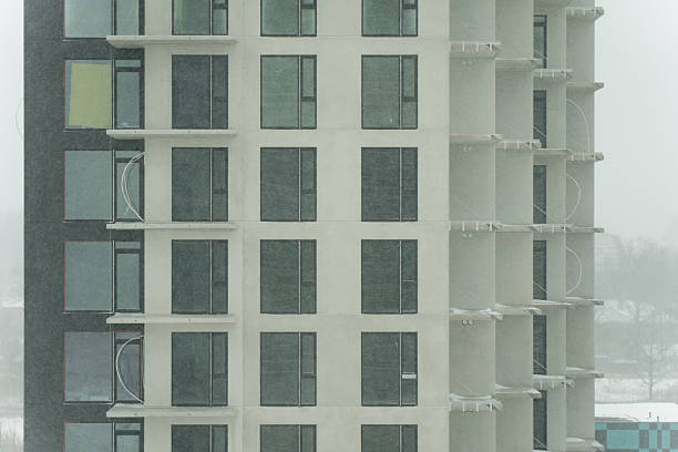 Modern residential building elevation with dark side wall, glass window panels and balcony columns, real estate architecture background and copy space