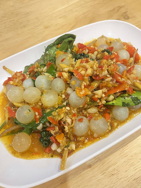 Spicy Thai salad with translucent fish balls, chili, garlic and herbs on white plate, vibrant and aromatic