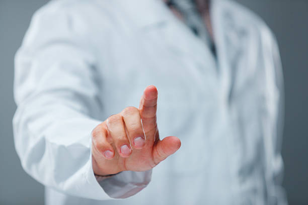 Close-up of an unrecognizable doctor in a white coat with stethoscope pointing and touching an invisible touchscreen. Concept of telemedicine, digital healthcare, medical apps and online consultation.