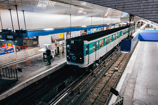 Paris, France - A teal and white metro train entering an underground subway station with illuminated platform signage, tiled walls, and urban commuters in motion, capturing everyday public transportation life inside the Parisian metro network with dynamic perspective and travel atmosphere