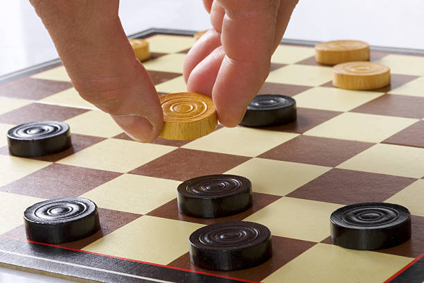 Close-up of a man's hand playing checkers on a chessboard