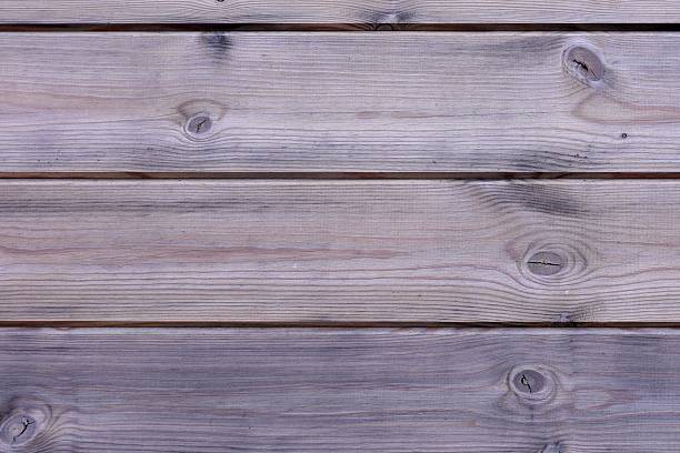 Close-up detail of a rustic wooden wall with visible grain, knots, and natural aging marks. The vertical post contrasts with horizontal planks, while a softly blurred outdoor background adds depth. Ideal for concepts such as craftsmanship, sustainability, rural architecture, natural materials, and minimal design.