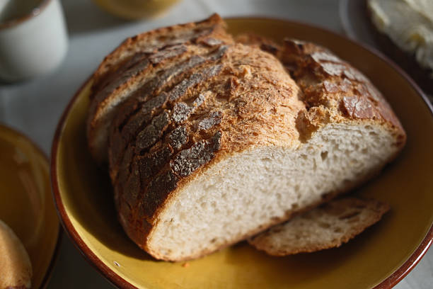 Fresh artisan bread loaf placed on a rustic wooden table. The image highlights natural texture, golden crust, and traditional baking craftsmanship. Ideal for themes such as bakery, homemade food, comfort meals, and Mediterranean lifestyle.