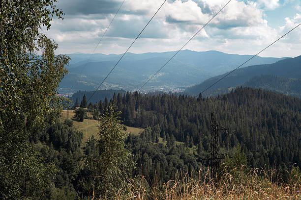 In the distant landscape, a mountain, road, and electricity cables converge, offering a scenic journey through the highland power-infused terrain.