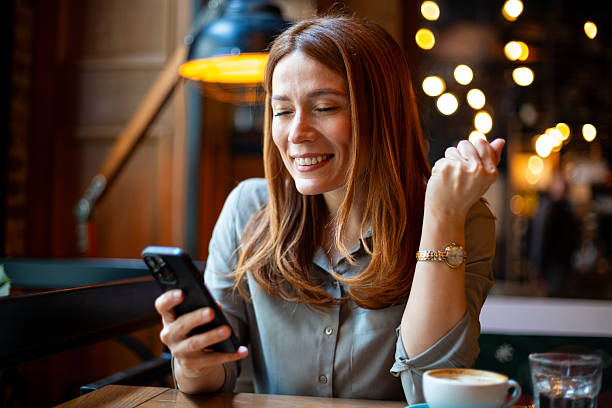 Woman laughing using smartphone in cafe