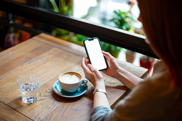 Woman using smartphone with blank screen in cafe