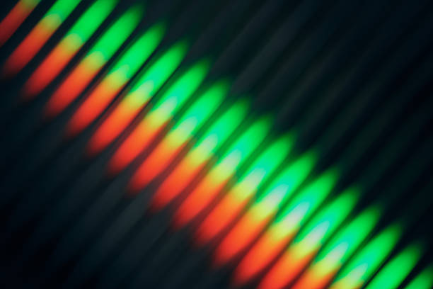 Light refraction forms vibrant red, orange, yellow, and green diagonal lines on a dark background