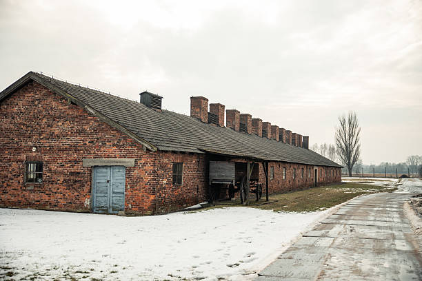 February 15, 2026, Poland. Auschwitz I brick barracks standing in snow under a gray winter sky, a solemn reminder of the Holocaust and World War II atrocities, memorial site and historic museum
