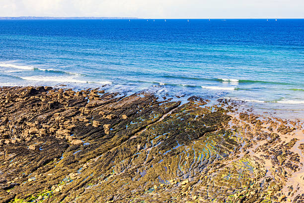 Rocky beach by the sea at low tide with breaking waves