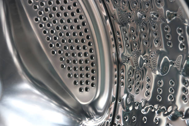 View of a modern front-loading washing machine drum, with clean, shiny stainless steel surface. The appliance represents household chores, laundry hygiene, and modern home technology.