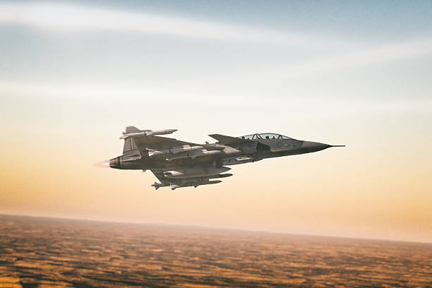 A JAS-39D Gripen Fighter Jet streaks through the sky, high above the sand dunes of a desert. Scale model photography