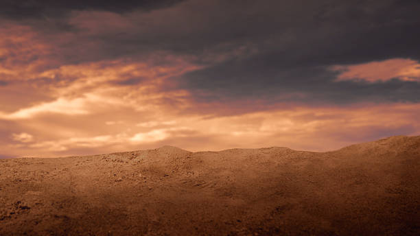 Dramatic low-angle view of a sandy desert mound under a fiery sunset sky with dark storm clouds and golden light. Ideal for cinematic backgrounds and conceptual themes