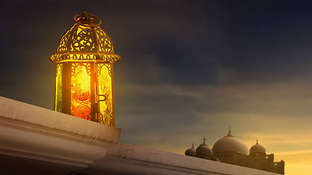 istock A traditional glowing Arabic lantern on a stone ledge with a blurred mosque silhouette and dramatic sunset sky background, representing Ramadan and Islamic culture 2262437870
