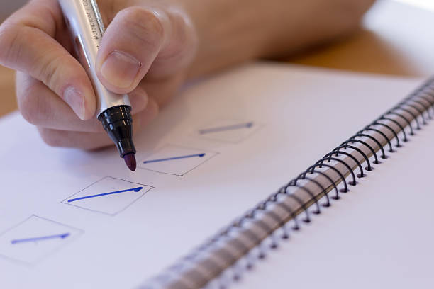 hand marking checklist boxes on spiral notebook with blue marker. Concept of task management, productivity, planning, goal setting, organization personal development.