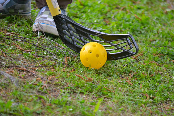 Child playing floorball outdoors on green grass, yellow floorball visible. Summer activity, active childhood and Finnish lifestyle concept. Bright seasonal photograph taken in Finland.