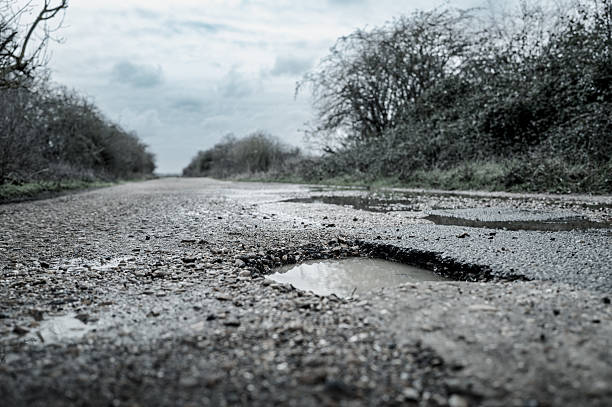 old road  potholes and holes outside city  cloudy autumn weather HDR
