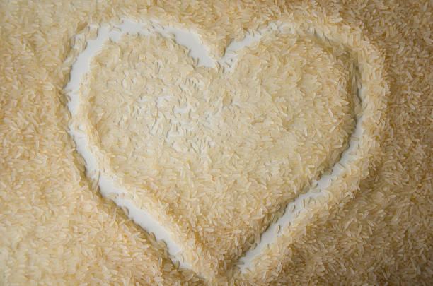 A heart shape is outlined in a pile of uncooked rice grains, symbolizing love, care, and food appreciation.