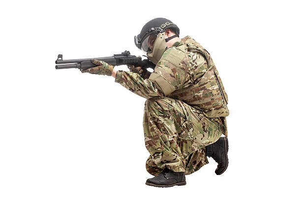 military commando in uniform with a shotgun attacks and aims on a white isolated background, soldier in action