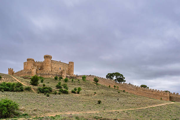 Berlanga de Duero, Soria, Spain - May 5, 2010: Ruins of a medieval castle on a hill in Castile-Leon, on the Spanish meseta in early spring, under a heavily clouded sky but with the castle partly in sunlight.