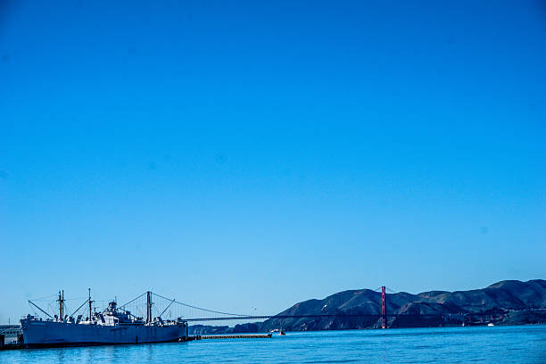 A large ship is docked at the pier. The sky is clear and blue, and the water is calm