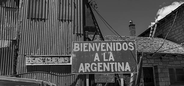 Plano medio de un galpón con una ventana de vidrios quebrados, resaltando la decadencia industrial frente al cielo de montaña