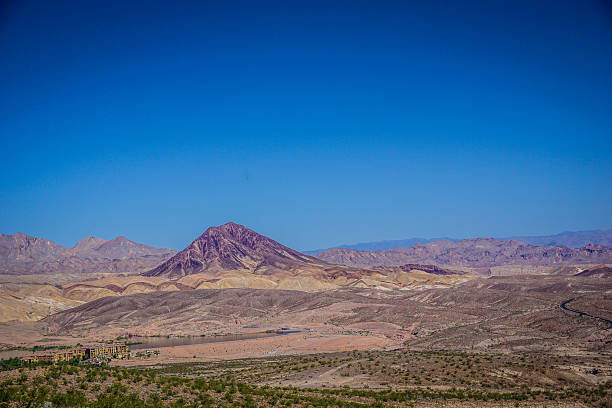A mountain range is visible in the distance with a clear blue sky. The mountains are covered in brown rocks and the sky is a bright blue