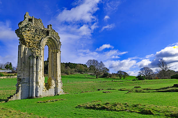The round tower and arched entrance of an old and derelict monastery that was abandoned in the medieval times. Captured on a grey and overcast winter day.
