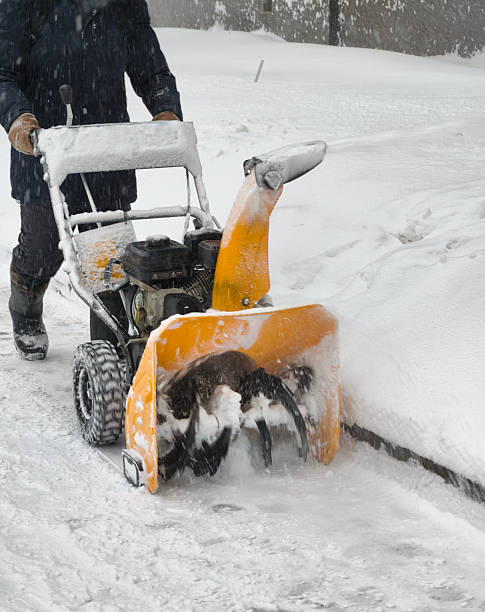 Self-propelled gasoline snow blower clearing heavy snow from a sidewalk during heavy snow blizzard