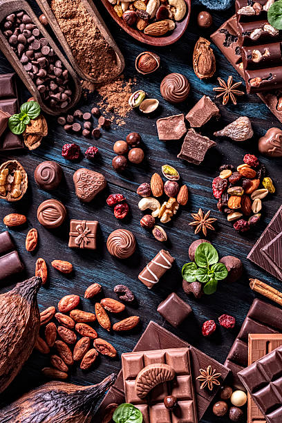 Table top view of an assortment of chocolate, nuts and dried fruit on a rustic table.