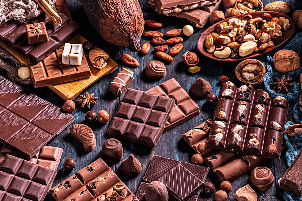 High angle view of an assortment of chocolate, nuts and dried fruit on a rustic table.