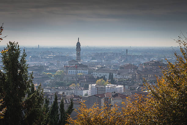 Autumn cityscape with statue-topped clock tower framed by hillside trees