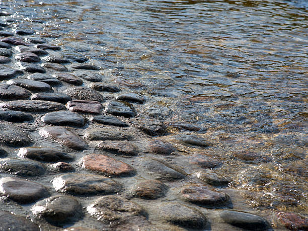 Natural shining granite stones on the river embankment, clear water
