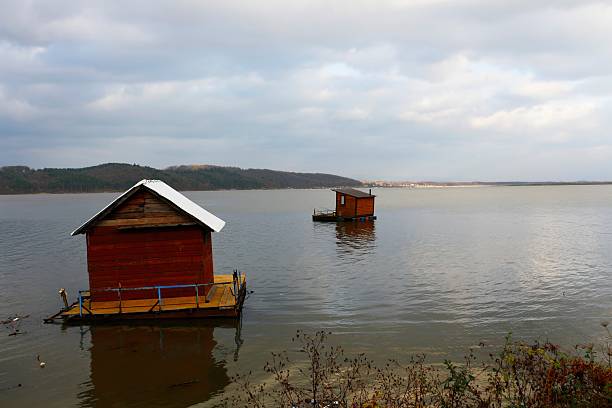 Floating houses resting on the calm waters of Lake Modrac, surrounded by natural scenery
