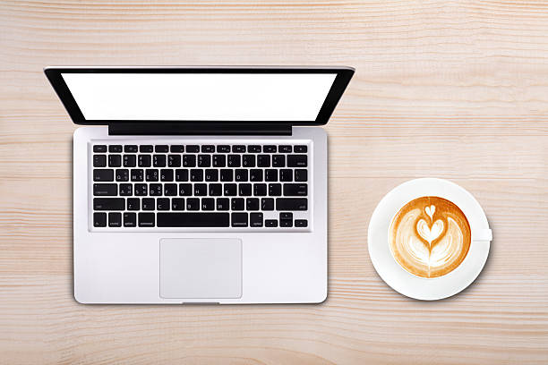 Top view cup of latte art coffee and laptop computer notebook on wooden table