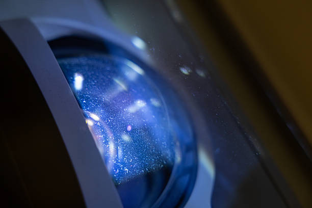 A blue lens with a blue light shining through it. projector is used for a system of lenses for projecting slides or film onto a screen.