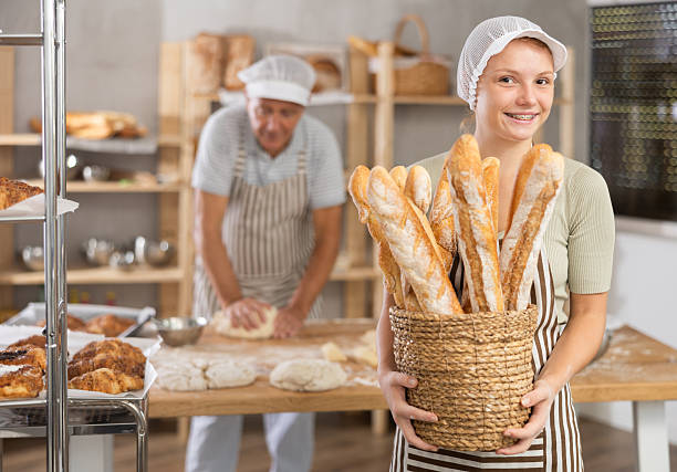Young woman baker with basket of baguettes